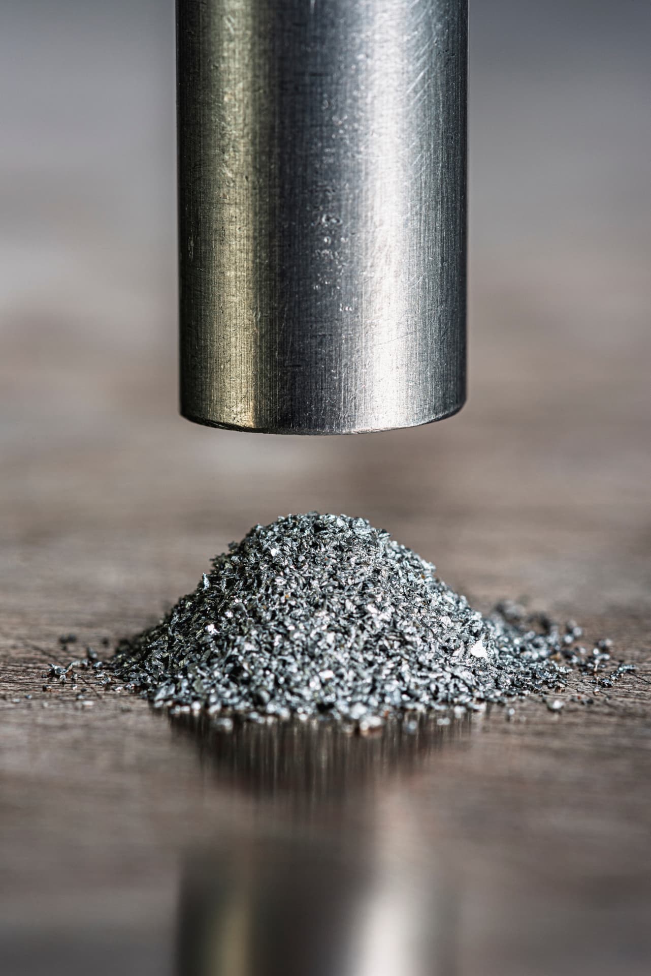Machined metal rod end above a pile of atomized metal powder