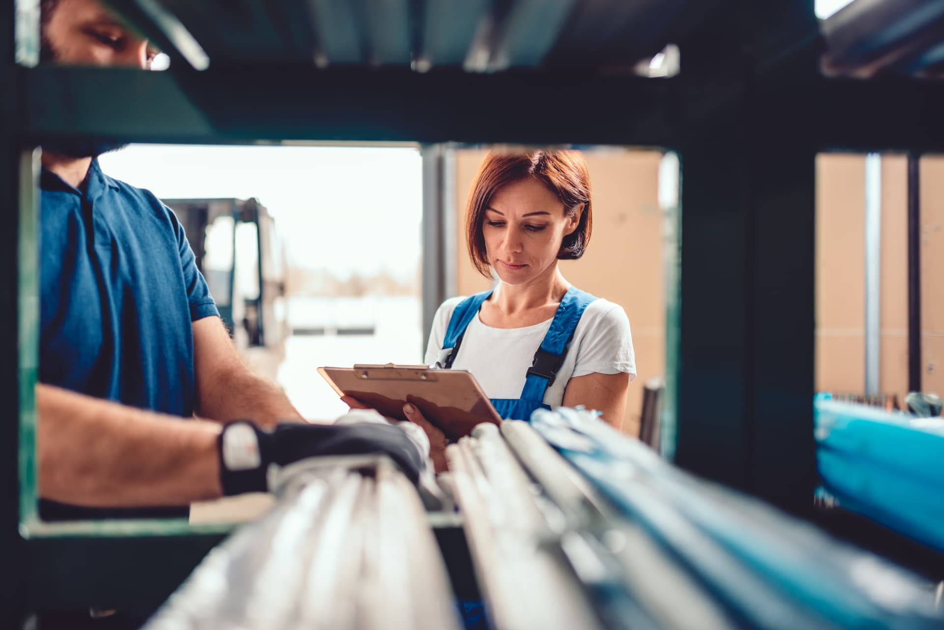 Two Alloy team members reviewing a clipboard while checking materials on a storage rack